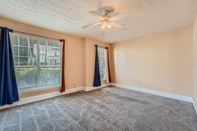 carpeted spare room with baseboards, a ceiling fan, and a textured ceiling