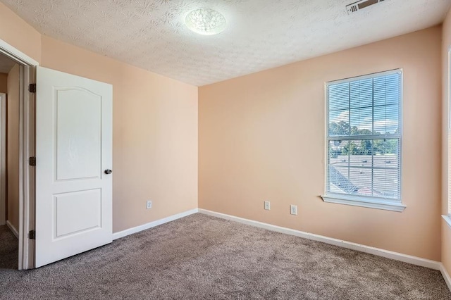 carpeted empty room featuring a textured ceiling, visible vents, and baseboards