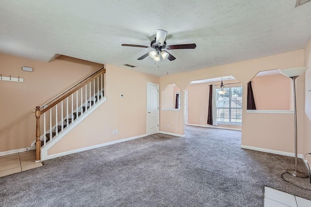 unfurnished living room with baseboards, ceiling fan, stairs, and a textured ceiling