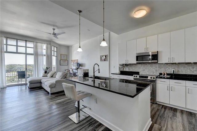 kitchen featuring white cabinets, appliances with stainless steel finishes, sink, and an island with sink