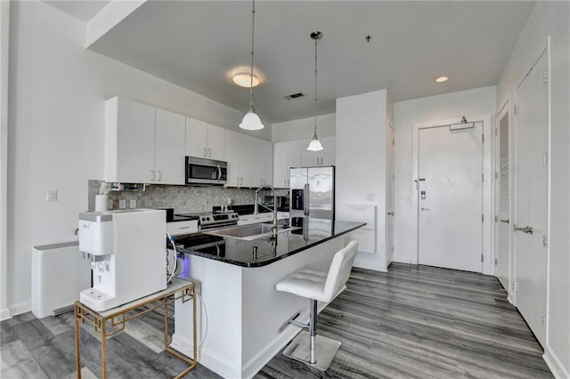 kitchen featuring stainless steel appliances, sink, a breakfast bar, white cabinets, and a kitchen island with sink