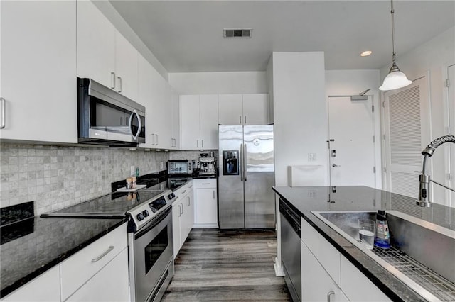 kitchen with dark wood-type flooring, sink, white cabinetry, appliances with stainless steel finishes, and decorative light fixtures