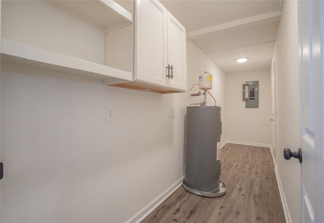 laundry area featuring water heater, baseboards, light wood-type flooring, and electric panel