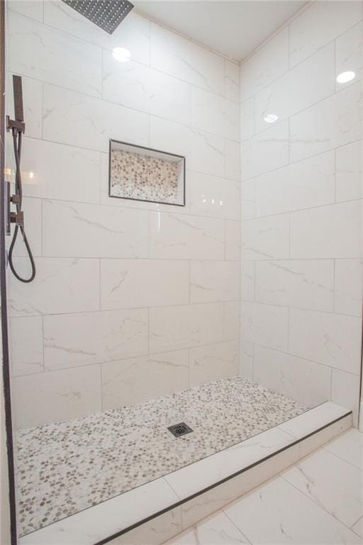 full bathroom with tiled shower and marble finish floor