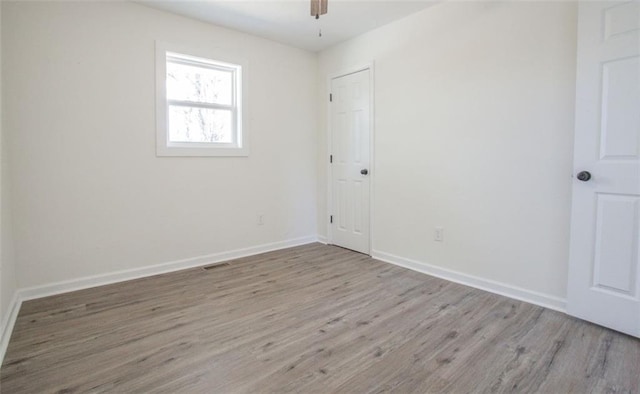 unfurnished room featuring ceiling fan, visible vents, baseboards, and wood finished floors