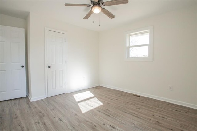 unfurnished bedroom with a ceiling fan, wood finished floors, visible vents, and baseboards