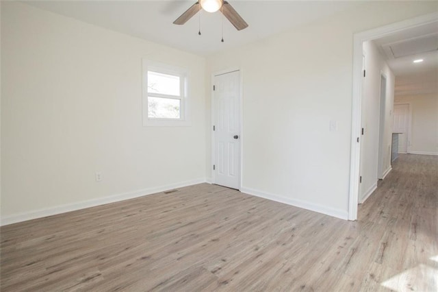 empty room with visible vents, light wood-style flooring, a ceiling fan, and baseboards