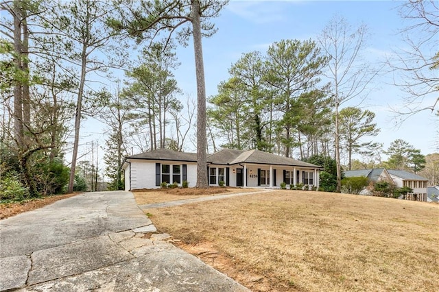 ranch-style home featuring covered porch and a front yard