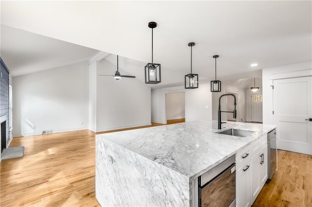 kitchen with sink, dishwasher, a kitchen island with sink, light stone counters, and white cabinets