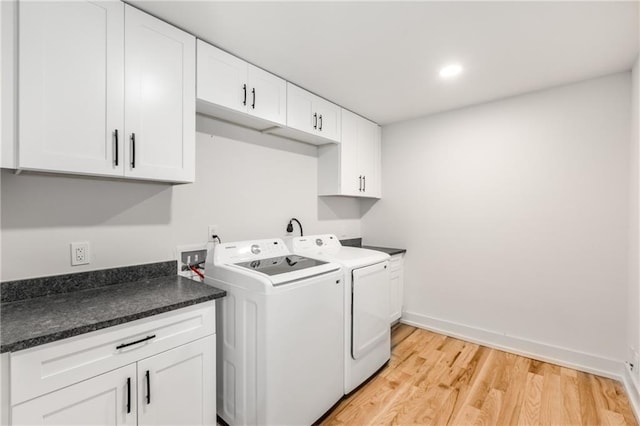 laundry room with washing machine and dryer, cabinets, and light wood-type flooring