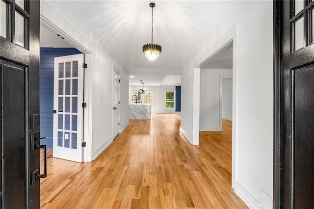 hall with an inviting chandelier and light hardwood / wood-style floors