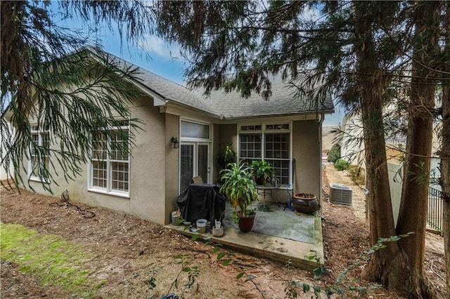 view of home's exterior with a patio, fence, central AC, a shingled roof, and stucco siding