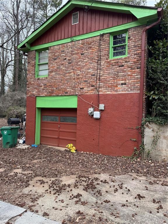 view of side of property with driveway, brick siding, board and batten siding, and an attached garage