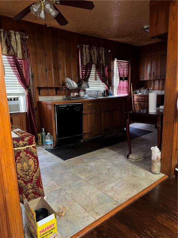 kitchen featuring black dishwasher, a healthy amount of sunlight, cooling unit, and wood walls