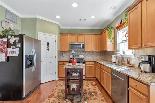 kitchen with visible vents, ornamental molding, a sink, appliances with stainless steel finishes, and light wood finished floors