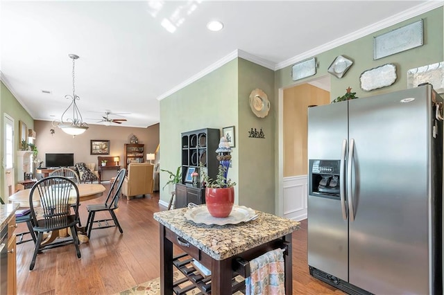 kitchen featuring light wood-style flooring, ceiling fan, hanging light fixtures, ornamental molding, and stainless steel refrigerator with ice dispenser