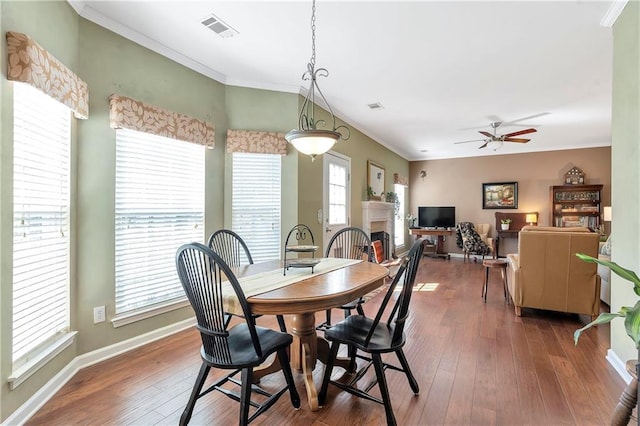 dining space featuring visible vents, crown molding, baseboards, hardwood / wood-style floors, and a fireplace