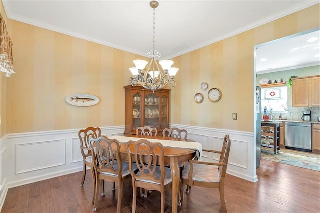 dining area featuring light wood-type flooring, a wainscoted wall, ornamental molding, and a chandelier