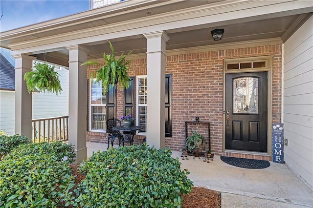 entrance to property featuring brick siding and covered porch