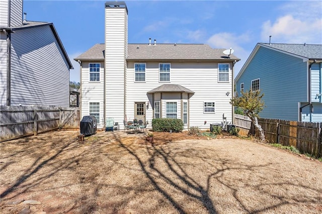 back of property featuring a fenced backyard and a chimney