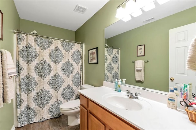 bathroom featuring vanity, toilet, wood finished floors, and visible vents