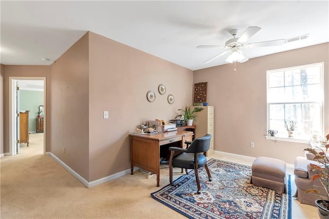 office space featuring a ceiling fan, visible vents, light colored carpet, and baseboards