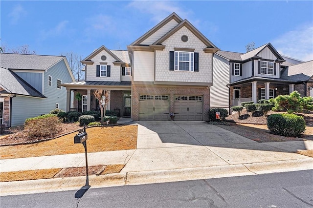 craftsman-style home with brick siding, an attached garage, covered porch, driveway, and a standing seam roof