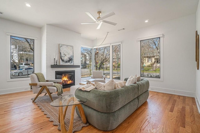 living room with light wood finished floors, a fireplace, baseboards, and a wealth of natural light