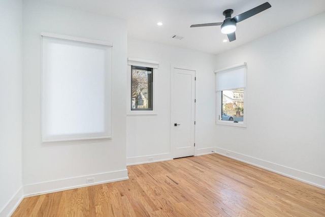 unfurnished room with baseboards, a healthy amount of sunlight, visible vents, and light wood finished floors