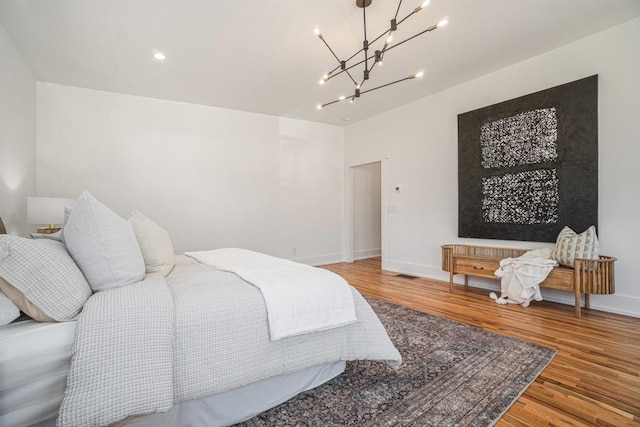 bedroom with a notable chandelier, baseboards, and wood finished floors