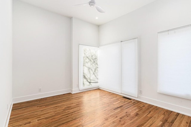 empty room featuring a ceiling fan, baseboards, visible vents, and wood finished floors