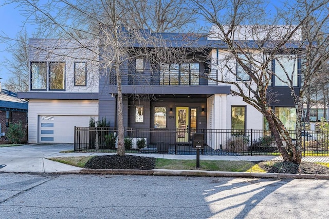 view of front of property with a balcony, driveway, a fenced front yard, and an attached garage