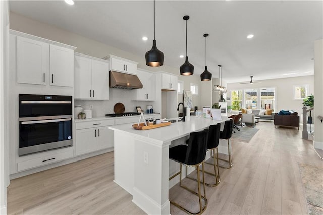 1941 Quarry Park Pl NW, Atlanta, GA 30318 - kitchen featuring double oven, under cabinet range hood, white cabinetry, open floor plan, and light countertops