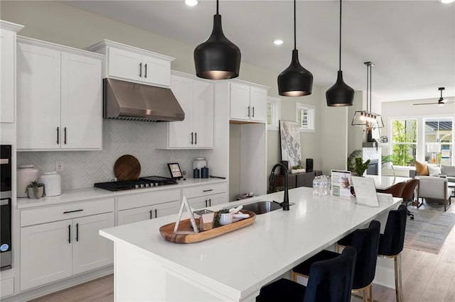 1941 Quarry Park Pl NW, Atlanta, GA 30318 - kitchen with under cabinet range hood, black gas cooktop, light wood finished floors, decorative backsplash, and recessed lighting