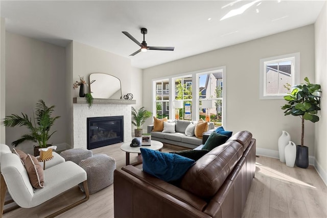 1941 Quarry Park Pl NW, Atlanta, GA 30318 - living room featuring a brick fireplace, light wood-style flooring, ceiling fan, and baseboards