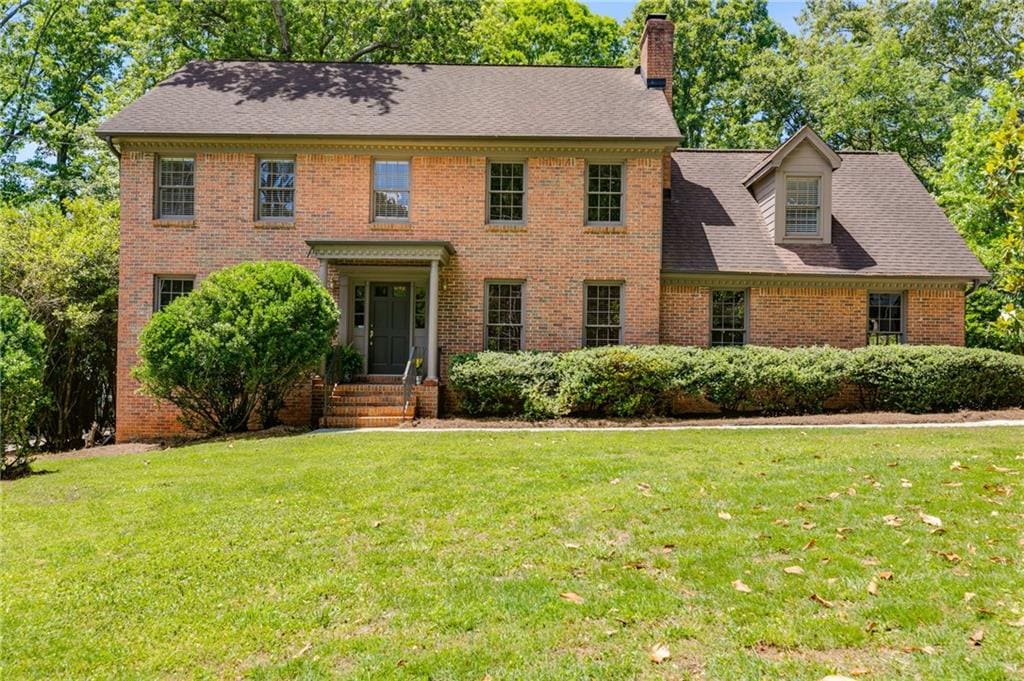 5124 Vermack Rd, Dunwoody, GA 30338 - colonial house featuring a front lawn, brick siding, a chimney, and a shingled roof