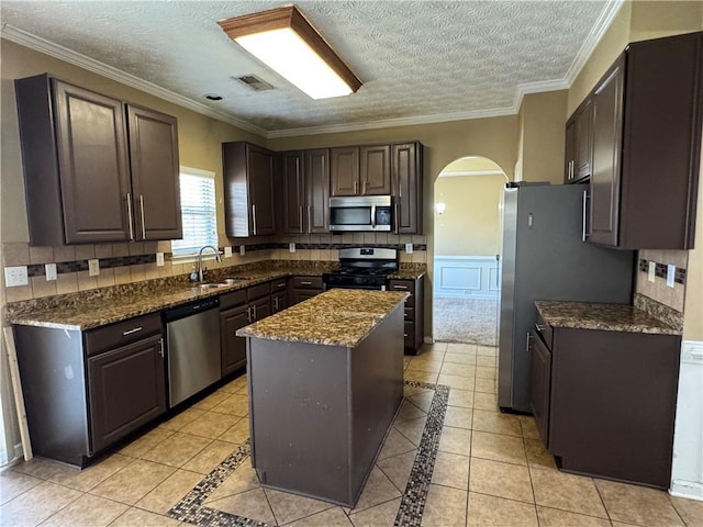 kitchen featuring a center island, stainless steel appliances, crown molding, a textured ceiling, and light tile patterned flooring