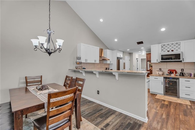 dining room featuring dark hardwood / wood-style floors, high vaulted ceiling, and beverage cooler