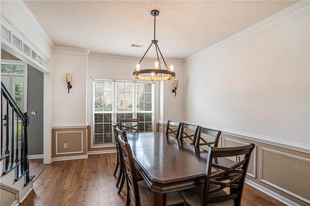 dining area featuring crown molding, dark hardwood / wood-style floors, and an inviting chandelier