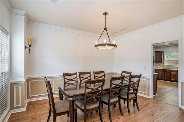 dining space with an inviting chandelier, crown molding, and light hardwood / wood-style flooring