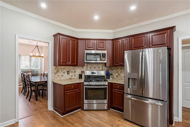 kitchen featuring an inviting chandelier, tasteful backsplash, light stone counters, appliances with stainless steel finishes, and light wood-type flooring