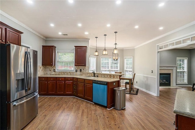 kitchen featuring sink, stainless steel appliances, decorative light fixtures, and ornamental molding