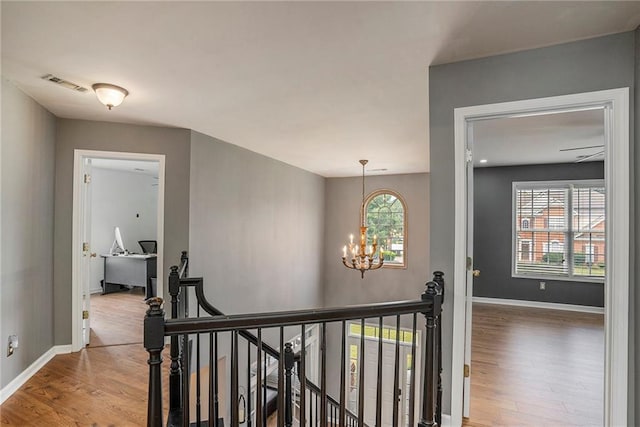 corridor featuring hardwood / wood-style flooring and an inviting chandelier