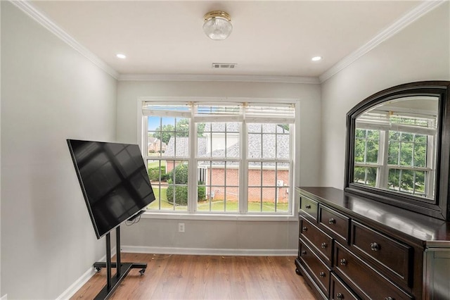 exercise room featuring crown molding and light hardwood / wood-style flooring