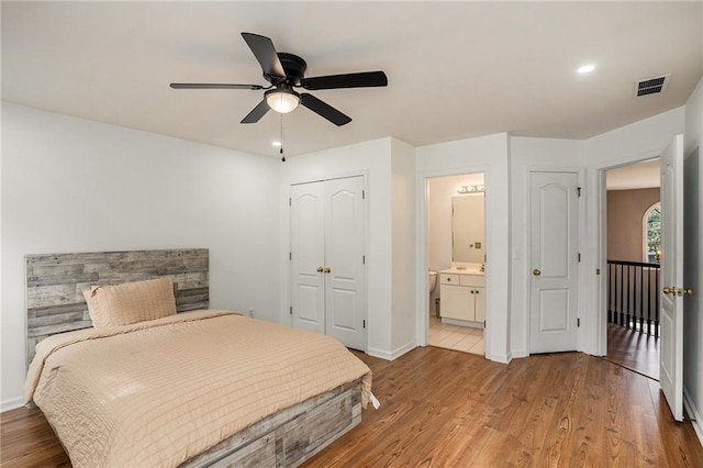 bedroom featuring ceiling fan, a closet, ensuite bathroom, and light hardwood / wood-style flooring