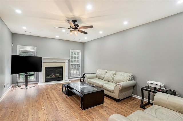 living room featuring ceiling fan, light hardwood / wood-style flooring, and a high end fireplace