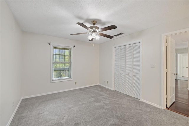 unfurnished bedroom featuring carpet flooring, a closet, baseboards, a ceiling fan, and a textured ceiling