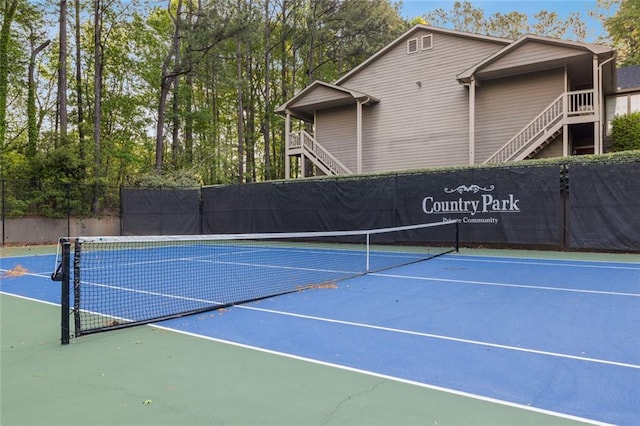 view of tennis court featuring fence and stairs