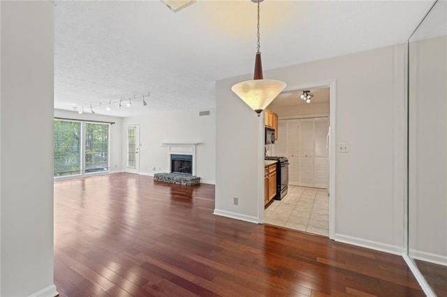 unfurnished living room featuring light wood finished floors, a fireplace with raised hearth, and baseboards