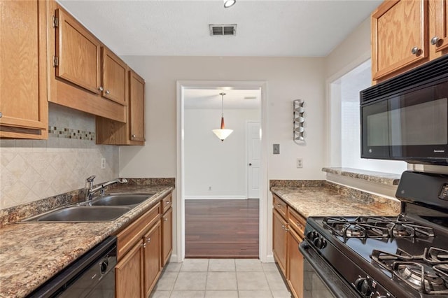 kitchen featuring black appliances, a sink, tasteful backsplash, light tile patterned floors, and brown cabinetry